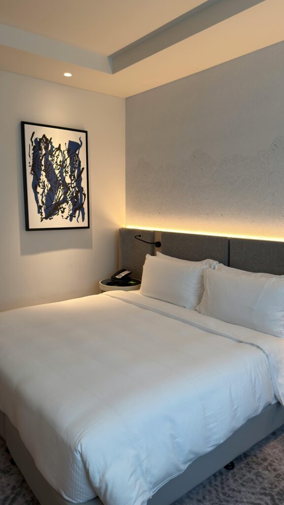 Elegant hotel room with modern decor, cozy bedding, and abstract art on the wall.
